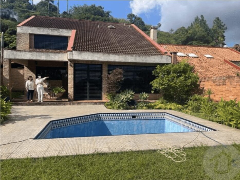 Fachada posterior de casa de lujo con piscina y áreas verdes en la Urbanización La Lagunita, Caracas.